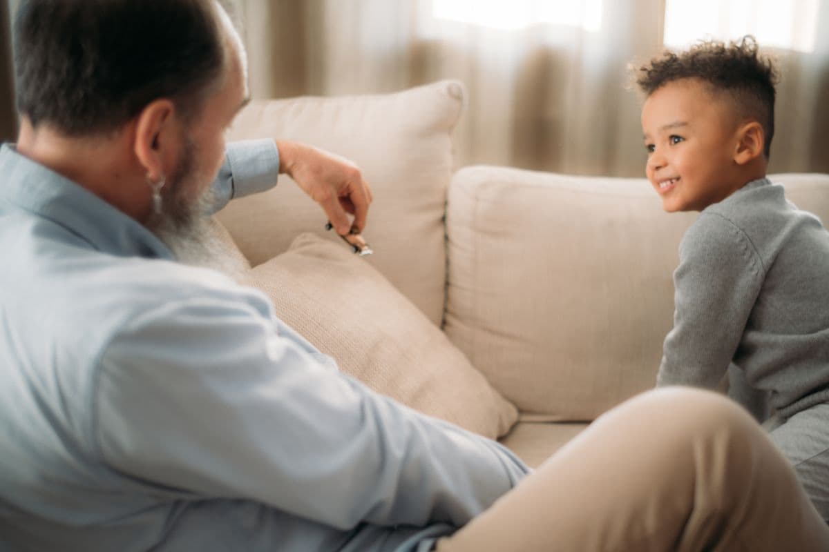 A grandfather and his grandson talking together on a couch